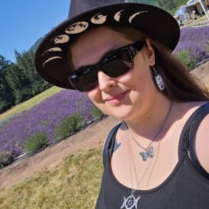 "Confident pet sitter wearing a moon-phase hat and sunglasses, smiling in front of a vibrant lavender field