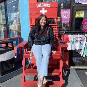 "Friendly pet sitter sitting on a bright red lifeguard chair, smiling in casual attire