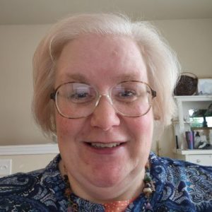 Kind-hearted pet sitter with short light hair and glasses, smiling warmly indoors